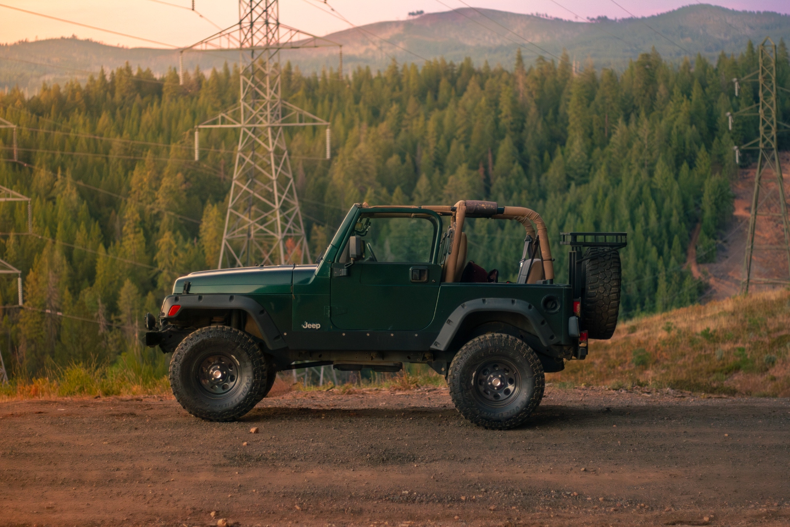 Jeep Wrangler TJ at golden hour against pine hills