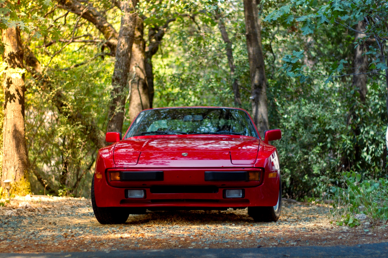 Red Porsche 944 front on forest road