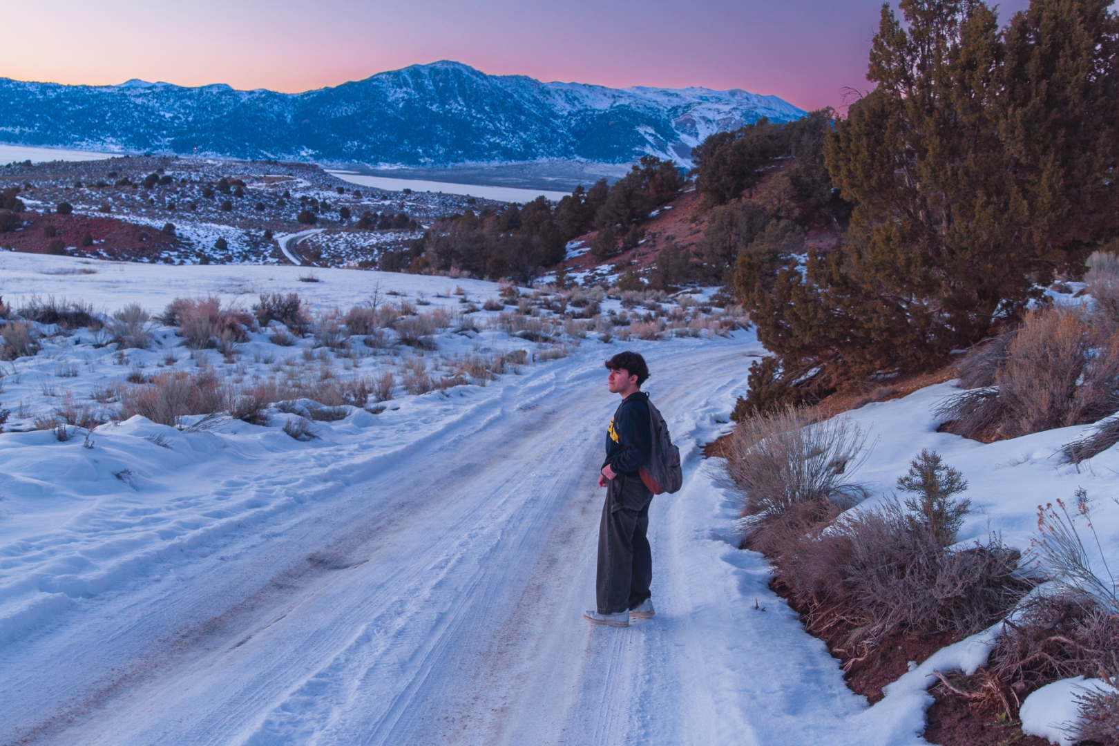 Figure standing on snowy road at dusk with Sierra Nevada mountains