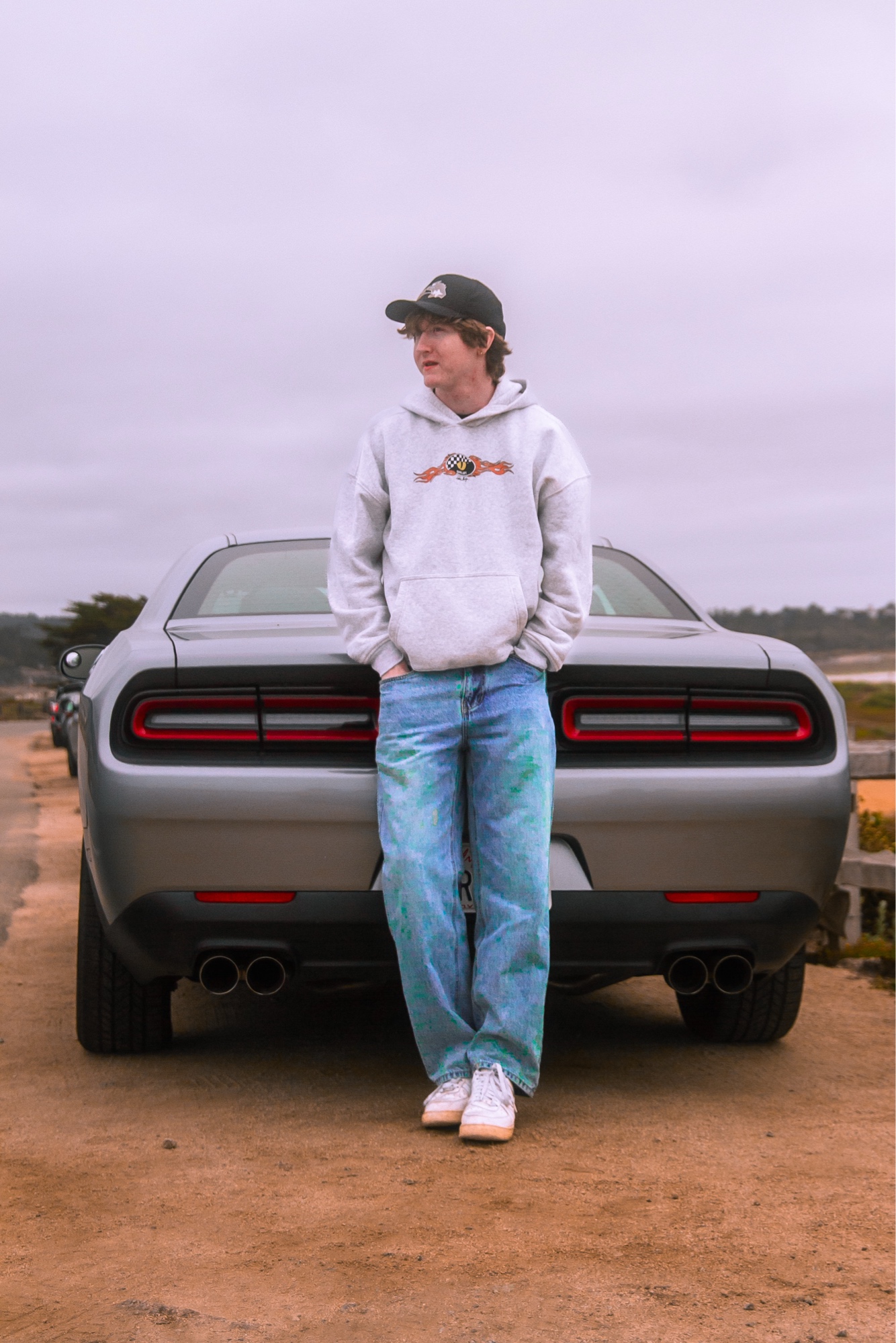 Person leaning on Dodge Challenger rear at Carmel, overcast sky