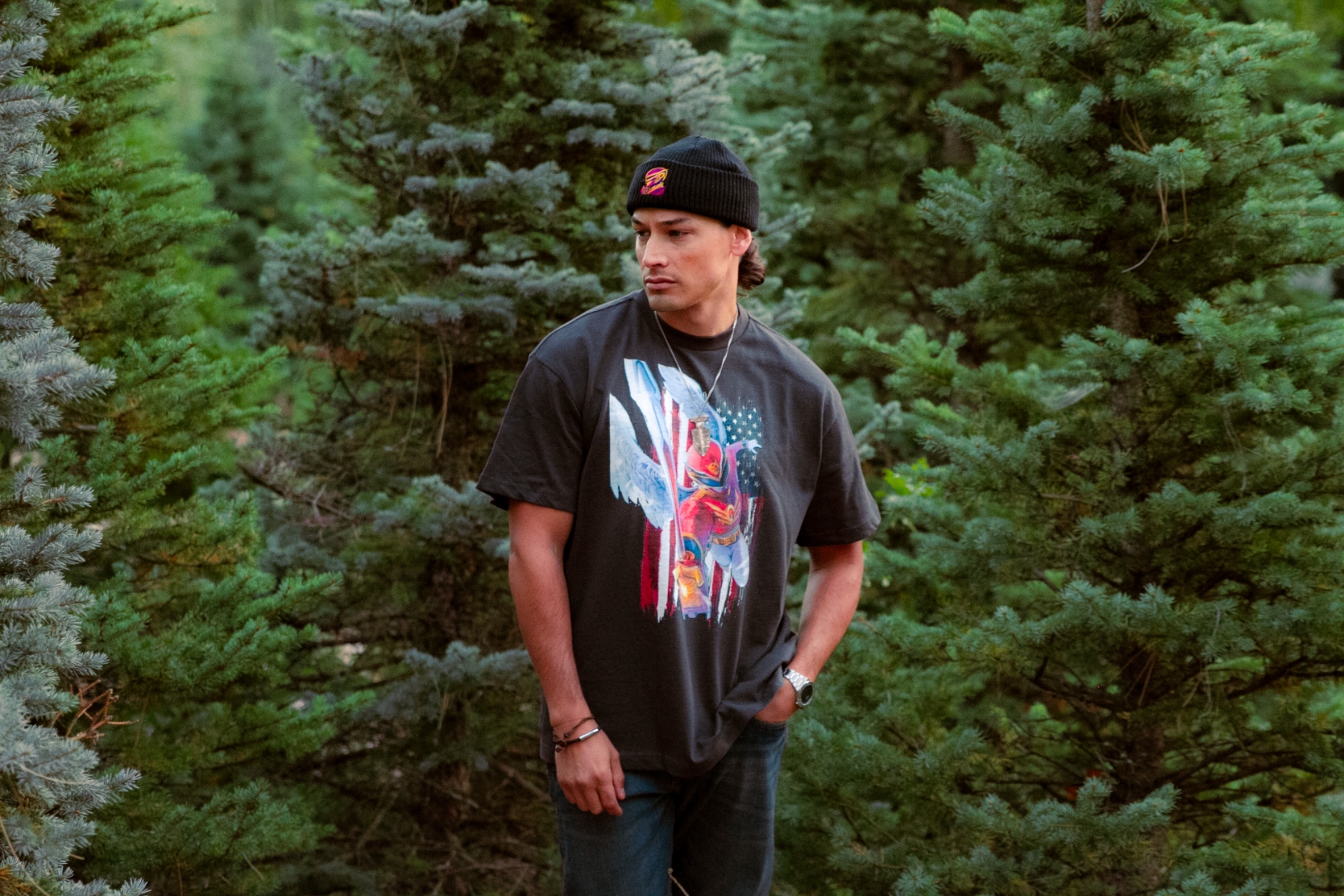 Man in beanie looking off-camera in pine forest