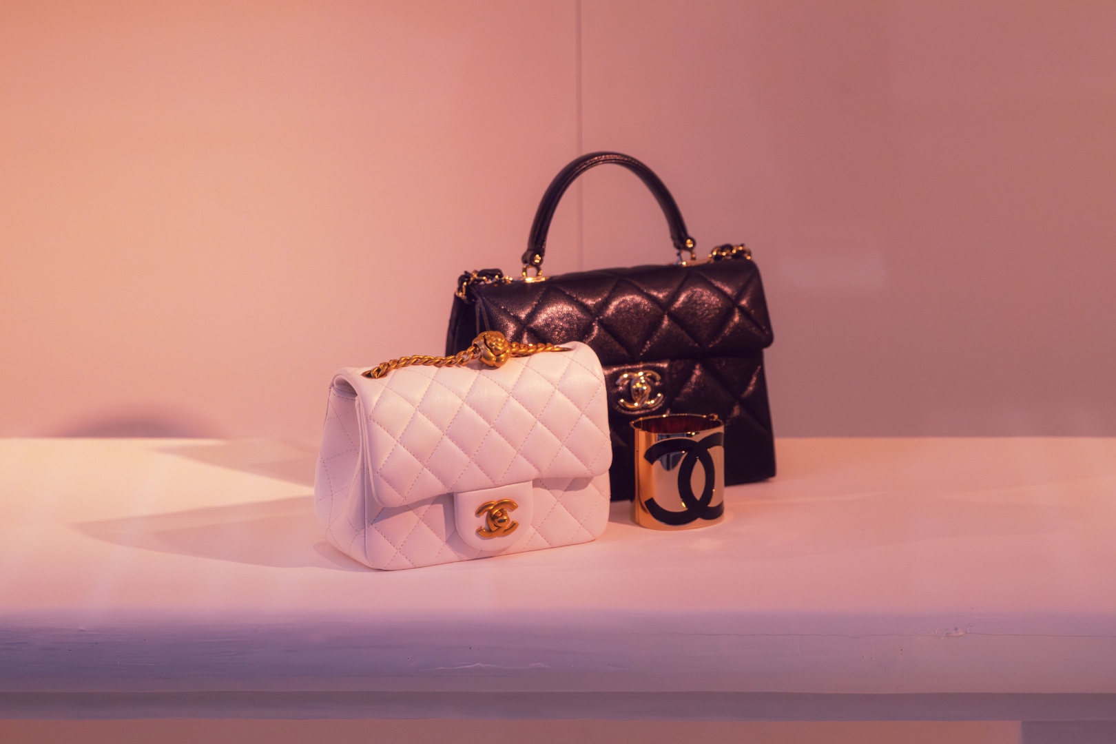 Chanel handbags and cuff bracelet on pink surface