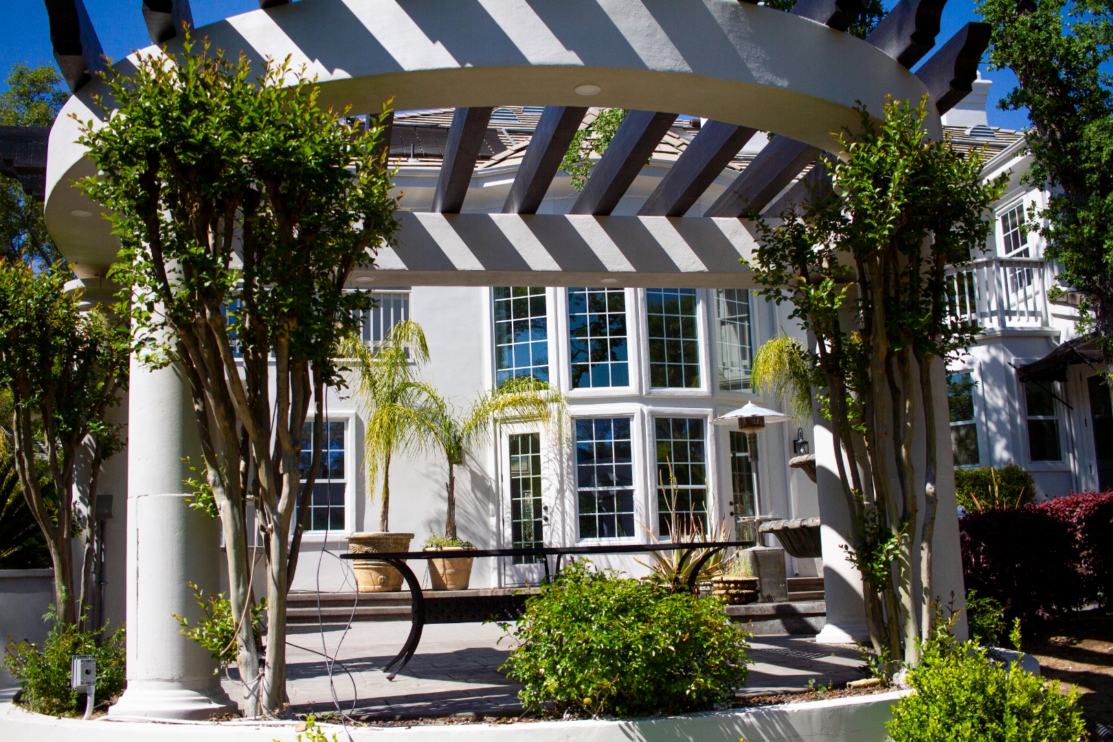 Curved white pergola with manicured garden and estate