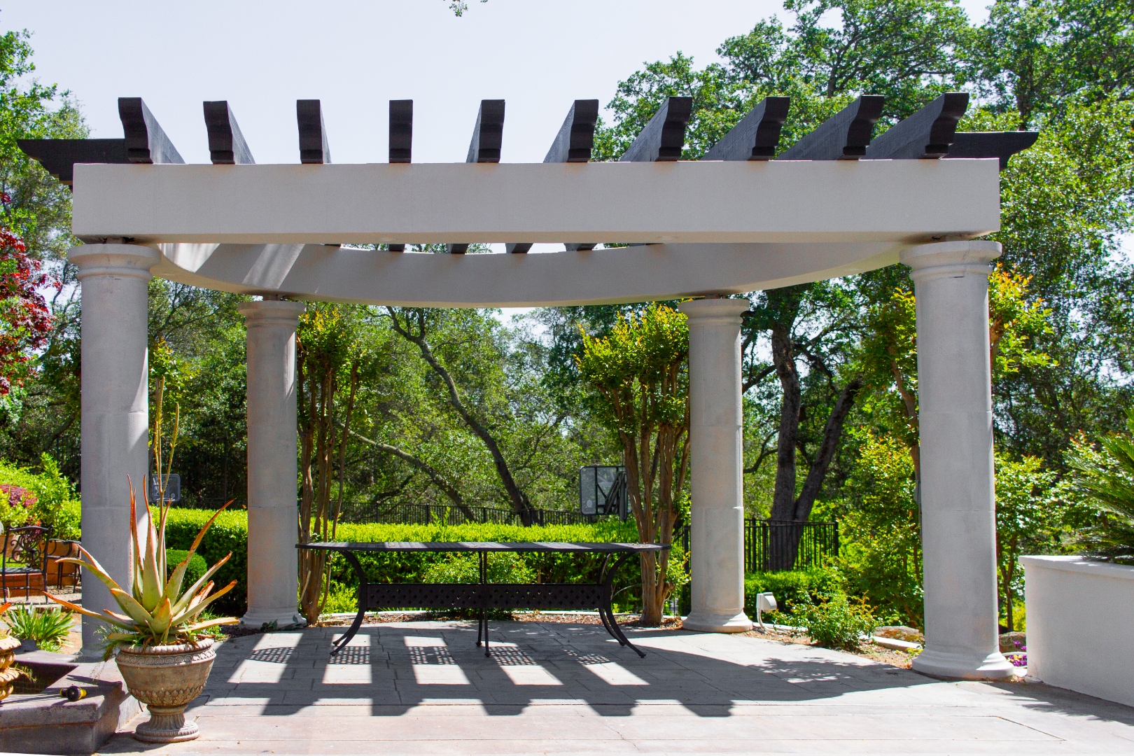 White pergola with classical columns over stone patio
