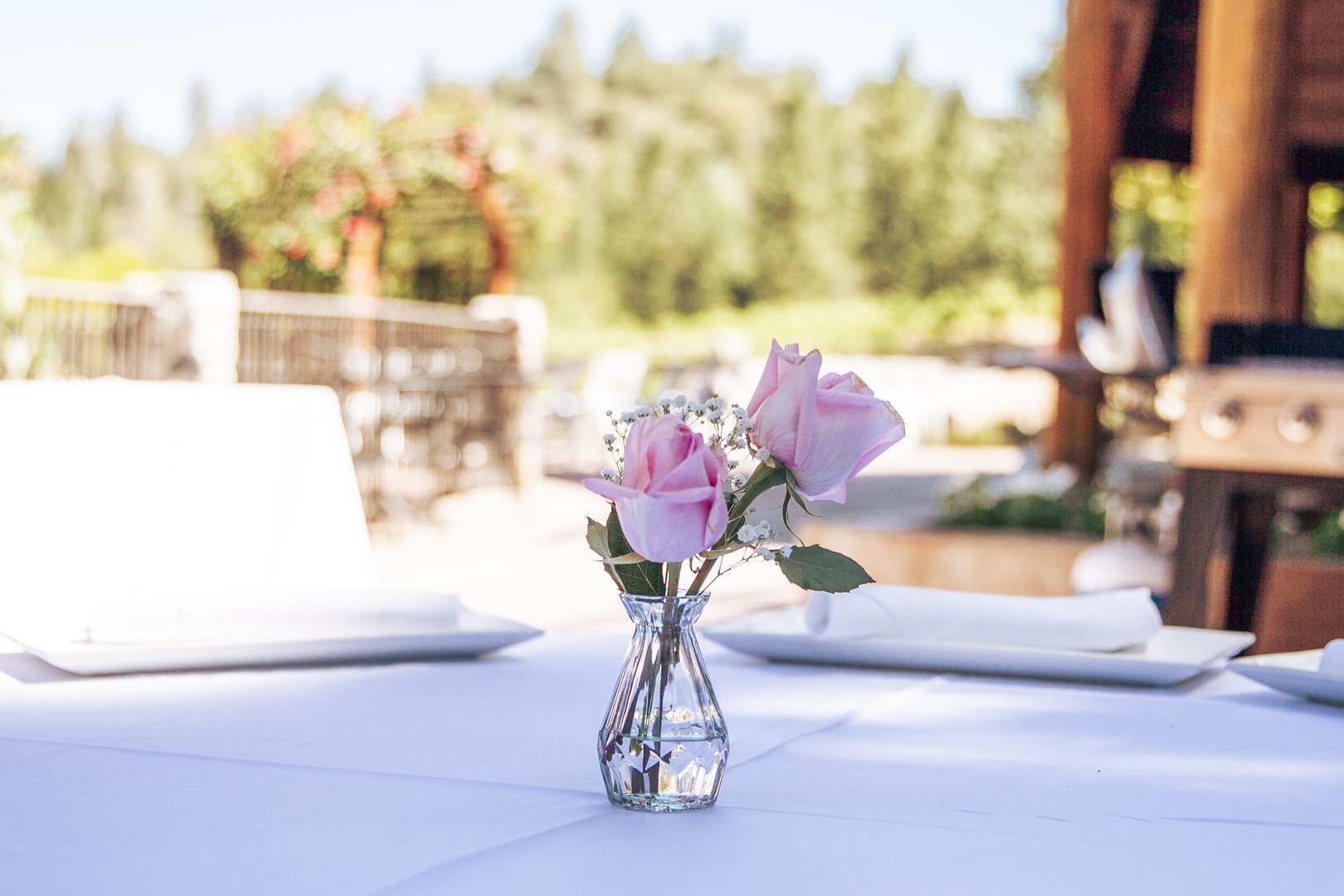 Single pink rose in a glass vase on a white linen reception table