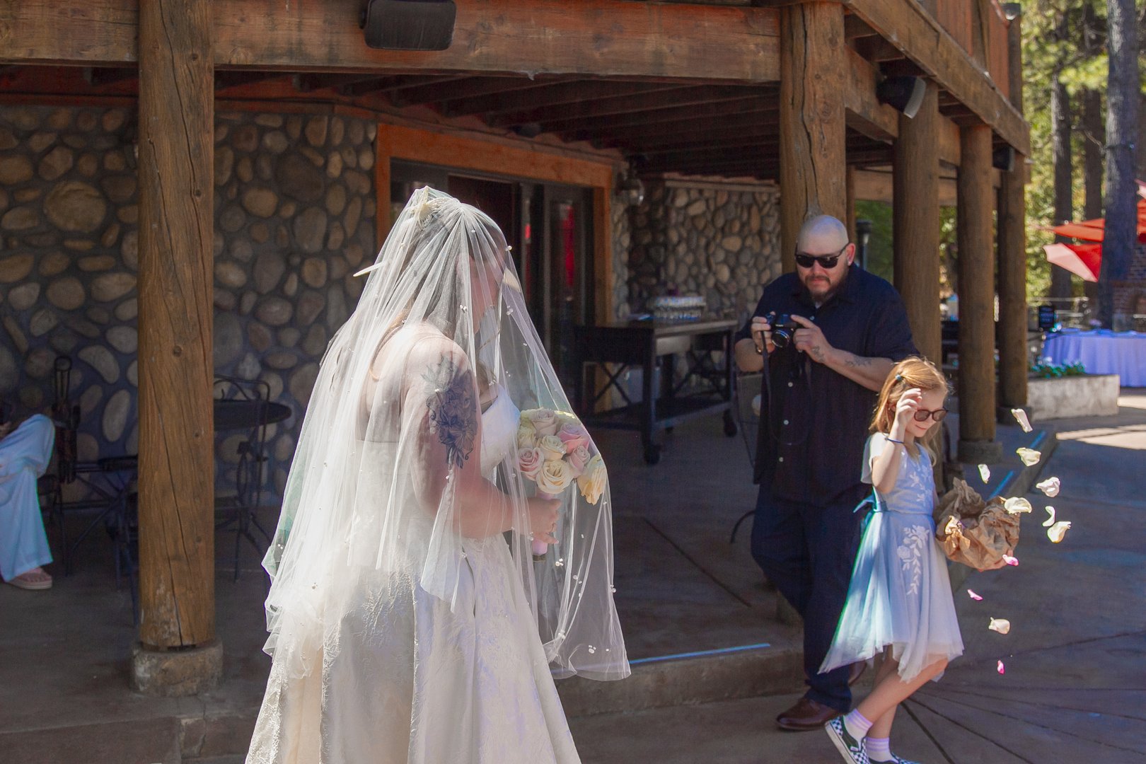 Bride in a cathedral veil walking to the ceremony with a flower girl scattering petals