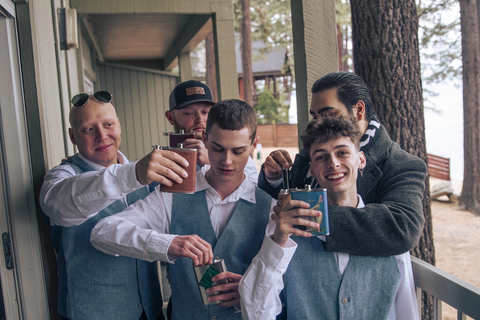 Groomsmen laughing and raising flasks together before the ceremony